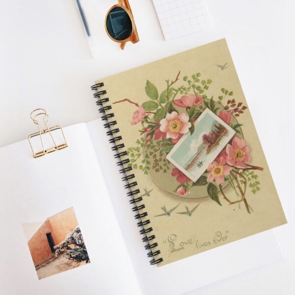 a spiral notebook with an ephemera cover on a flat surface with other office supplies